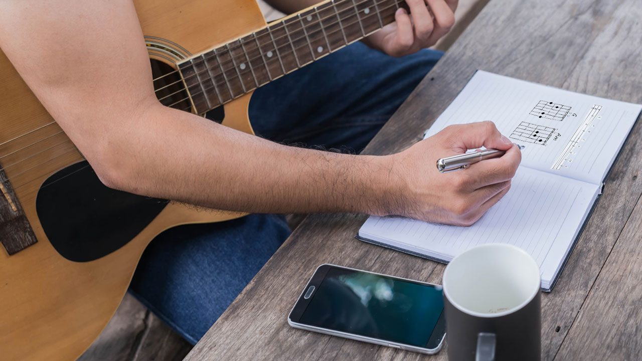 A person sitting down to write his own guitar tabs and chords